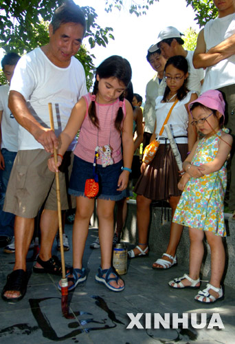 8月3日，浙大御跸社区的一位老伯伯在指导一名来自法国的华裔女孩在地上写水笔字。 &nbsp;&nbsp;&nbsp;&nbsp;当日，70多位来自6个不同国家的海外华裔少年来到杭州，参加以中华文化教育进社区为主题的“2006杭州寻根之旅夏令营活动”。他们在志愿者的带领下走进普通杭州居民家中，和社区居民一起体会传统的中国文化。新华社发（邵权达摄）